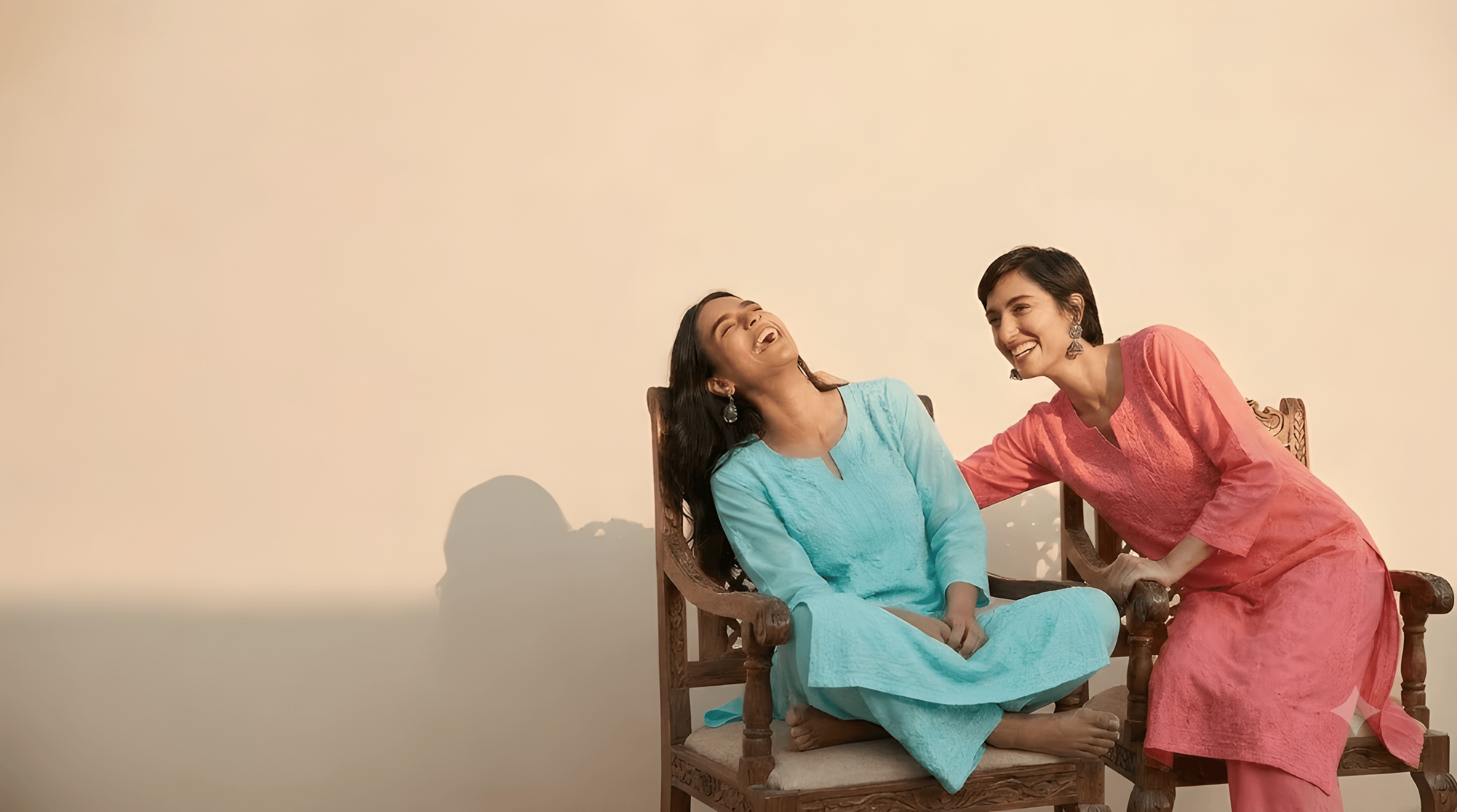 Two friends laughing together in hand-embroidered chikankari kurta sets